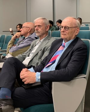 Three attendees sit in auditorium seating